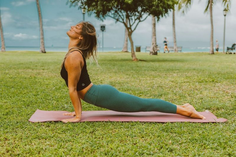 Woman practicing yoga on holiday on the grass with the sea in the background