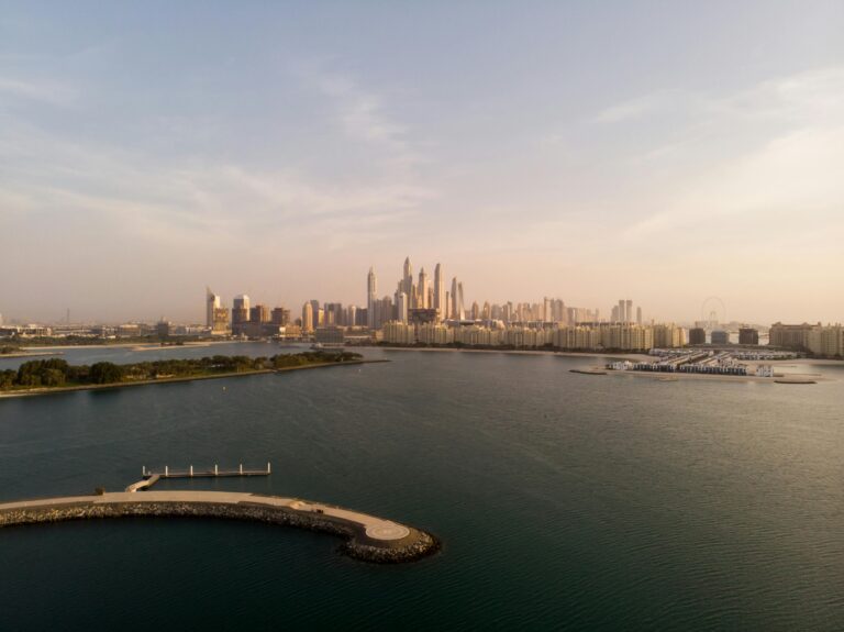 Serene aerial view of Dubai's skyline and coast during sunset, capturing the city's iconic architecture and tranquil waters.